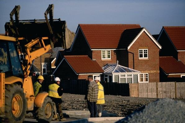 Aerial view of a UK new-build housing development with scaffolding and active roofing works.